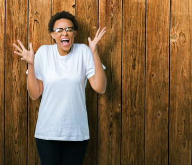 Arka plan deli kutluyor güzel genç Afro-Amerikan kadın üzerinde gözlük takan izole ve crazy arms ile başarı için kaldırdı ve heyecanlı çığlık gözler kapalı. Kazanan kavramı