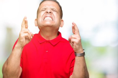 Orta yaş geçiş parmakları umut ve gözleri kapalı ile gülümseyen izole arka plan Arap adam. Şans ve batıl kavramı.