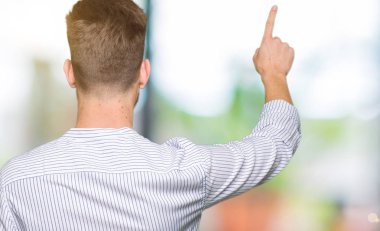 Geriye doğru arkasında parmak eliyle işaret Posing genç yakışıklı adam