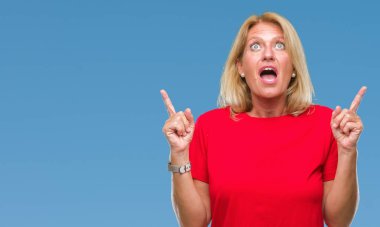 Orta yaş sarışın kadın izole arka plan üzerinden hayran ve yukarıya bakıp parmakları ile işaret şaşırttı ve silah kaldırdı.