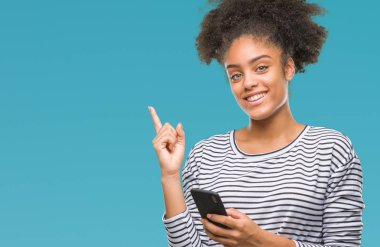 Genç afro Amerikalı kadın manifatura Smartphone izole arka tarafına el ve parmak ile işaret çok mutlu üzerinde kullanma
