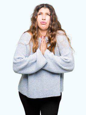 Kış kazak yalvarıyor ve umut ifade yüzünde çok duygusal ve endişe ile birlikte elleriyle dua giyen genç güzel kadın. Bağışlanmak. Din kavramı.