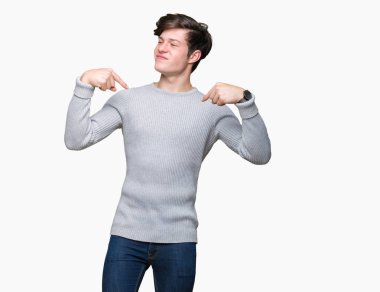 Yüzünde gülümseme ile kendinden emin görünüyorsun, kendini gururlu ve mutlu parmakları ile işaret izole arka plan üzerinde kış kazak giyen genç yakışıklı adam.