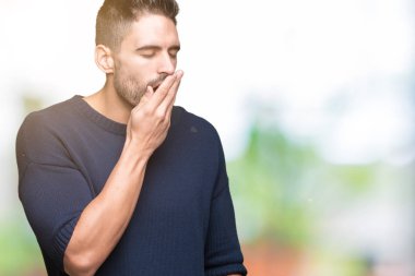 Genç yakışıklı adam kazak giyiyor izole arka plan üzerinde el ile ağız kapsayan yorgun esneme sıkılmış. Restless ve uyku hali.