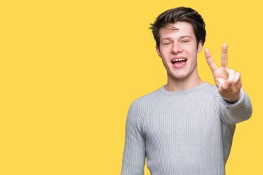 Gösterilen arka plan üzerinde kış kazak giyen genç yakışıklı adam izole ve parmakları ile işaret kendinden emin ve mutlu gülümseyerek ise ikinci.