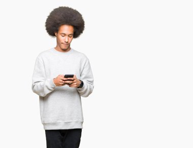 Genç African American Man ile afro saç akıllı yüz düşünme sağlam bir akıllı telefon kullanarak ciddi