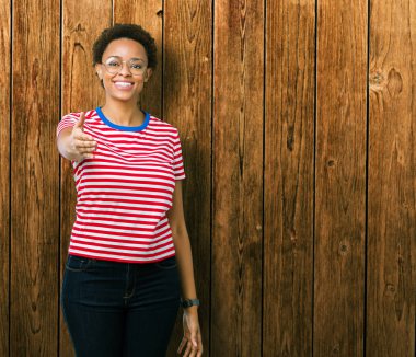 Tebrik ve davet edici dostu sunan karşılıklı gülümseyen izole arka plan üzerinde gözlük güzel genç Afro-Amerikan kadın. Başarılı iş.