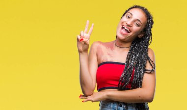 Genç mutlu yüz zafer işareti yaparken kameraya göz kırpıyor ile gülümseyen izole arka plan üzerinde pigmentasyon leke Doğum işareti ile Afrikalı-Amerikalı saç örgülü. İki numaralı.