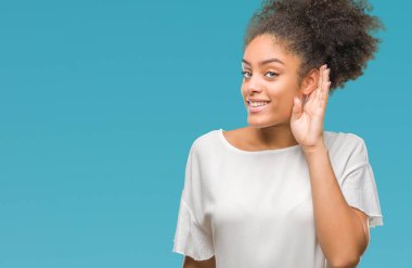 Bir işitme söylenti ya da dedikodu için dinleme kulak üzerinde el ile gülümseyen izole arka plan üzerinde genç afro Amerikalı kadın. Sağırlık kavramı.