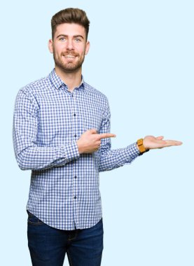 Hayret ve el ile sunulması ve parmak ile işaret ederken kameraya gülümseyen genç yakışıklı bussines adam.