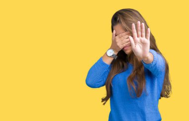 Üzerinde mavi kazak giyen genç güzel esmer kadın izole elleriyle gözlerini kapsayan arka plan ve stop jest ile acı ve korku ifadesi. Utandım ve negatif kavramı.