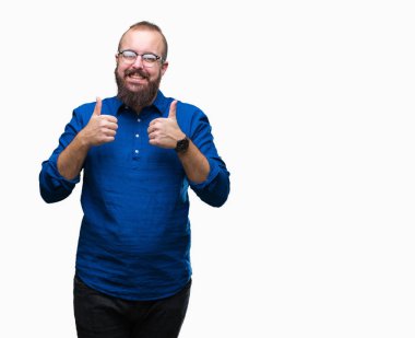 El ile pozitif jest yapıyor izole arka plan başarı işareti üzerinde gözlük takan Genç beyaz hipster adam başparmak gülümseyen ve mutlu. Neşeli bir ifadeyle, kazanan jest kameraya bakıyor.