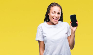 Ekran smartphone ayakta ve diş gösterilen kendine güvenen bir gülümsemeyle gülümseyerek mutlu bir yüz ile izole arka plan üzerinde gösterilen genç örgülü saç Afro-Amerikan Kız