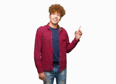 Yüzünde, kocaman bir gülümseme ile ceket afro saçlı Genç yakışıklı öğrenci adam kameraya bakarak yan el ve parmak ile işaret.