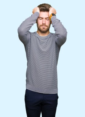 Genç yakışıklı adam giyen çizgili süveter çünkü umutsuz ve stresli baş ağrısı acı acı ve migren. Ellerini kafasına.