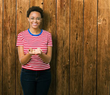 Güzel genç Afro-Amerikan kadın gözlük izole üzerine gülen alma veya jest vererek birlikte el avuç içi ile arka plan. Ayrı tutma ve koruma