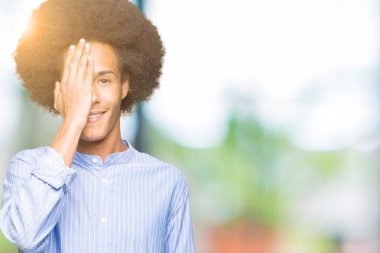 El yüz ve sürpriz duygu kendinden emin gülümseme ile tek gözüyle kapsayan afro saçlı genç Afro-Amerikan adam.