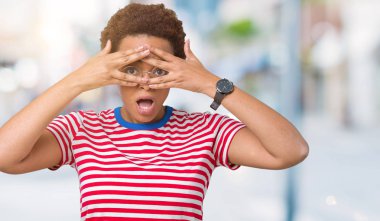 Mahcup ifadeyle parmaklarımın arasından yüz ve gözler el ile kapsayan şok bakmak izole arka plan üzerinde gözlük güzel genç Afro-Amerikan kadın arıyor.