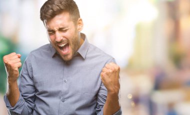 Soyutlanmış, mutlu ve heyecanlı genç bir adam kollarını kaldırmış, gülümseyen ve başarı için çığlık atan kazanan bir jest yapıyor. Kutlama konsepti.