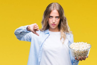 Kızgın yüz, eksi işareti aşağı antipati başparmak ile gösterilen, ret kavramı ile izole arka plan üzerinde patlamış mısır yemek güzel sarışın genç kadın