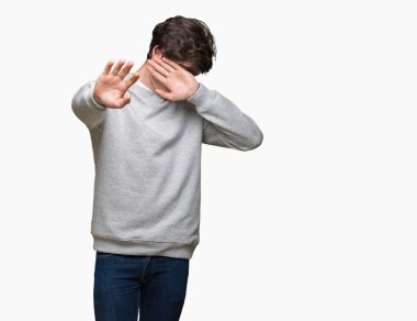 Üzerinde sweatshirt giyen genç yakışıklı sportif adam izole elleriyle gözlerini kapsayan arka plan ve stop jest ile acı ve korku ifadesi. Utandım ve negatif kavramı.