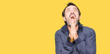 Orta yaş yakışıklı adam yalvarıyor ve elleri ile birlikte umut ifade yüzünde çok duygusal ve endişe ile dua bir ceket giyiyor. Bağışlanmak. Din kavramı.