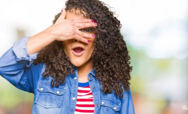 Mahcup ifadeyle parmaklarımın arasından arayan genç güzel kadın kıvırcık saçlı gözlüklü yüz ve gözler el ile kapsayan şok bakmak.