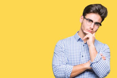 Çene düşünme hakkında soru, dalgın ifade üzerine el ile izole arka plan üzerinde gözlük takan yakışıklı delikanlı. Düşünceli yüzüyle gülümsüyor. Şüphe kavramı.
