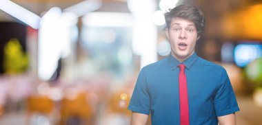 Korkuyor ve şok sürpriz ifade, korku ve heyecan yüz ile izole arka plan üzerinde kırmızı kravat giyen genç yakışıklı iş adamı.