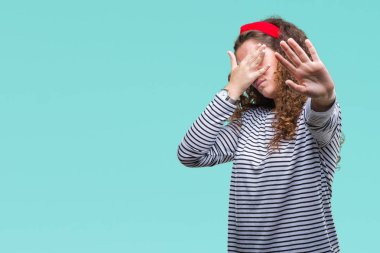 Güzel esmer kıvırcık saçlı Genç kız üzerinde çizgili süveter giyen izole elleriyle gözlerini kapsayan arka plan ve dur jest ile acı ve korku ifadesi. Utandım ve negatif kavramı.