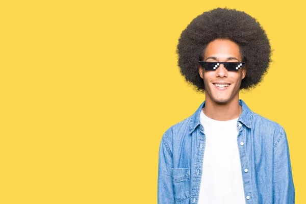 Young african american man with afro hair wearing thug life glasses with a happy and cool smile on face. Lucky person.