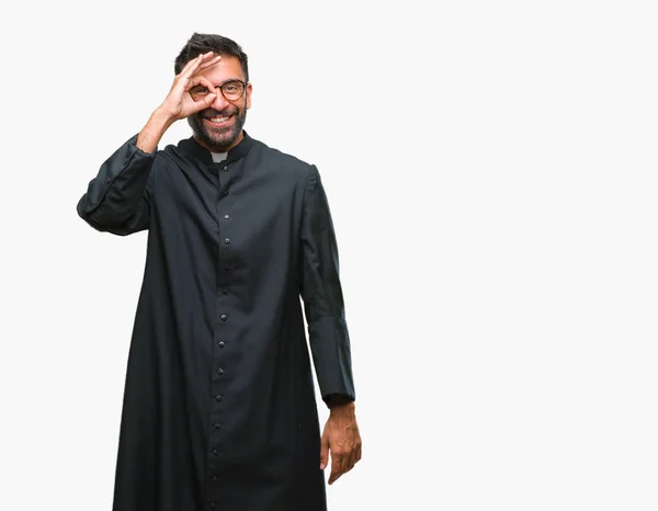 成人西班牙裔天主教神父在孤立的背景下做 手势用手微笑 眼睛看通过手指与愉快的面孔 — 图库照片