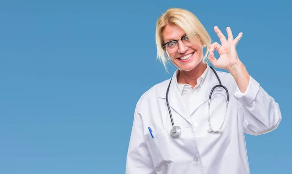 中年金发碧眼的医生妇女在孤立的背景微笑积极做确定的迹象与手和手指 成功的表达 — 图库照片