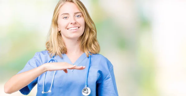 美丽的年轻医生妇女穿着医疗制服在孤立的背景示意与手显示大和大尺寸的标志 措施符号 看着镜头微笑 测量概念 — 图库照片