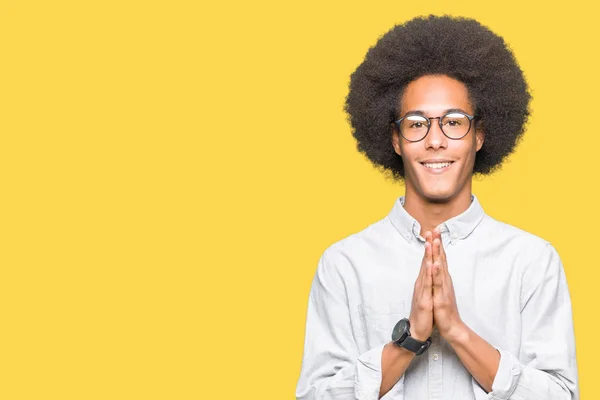 非洲青年美国男子戴着非洲头发戴眼镜祈祷双手一起请求原谅微笑的自信 — 图库照片