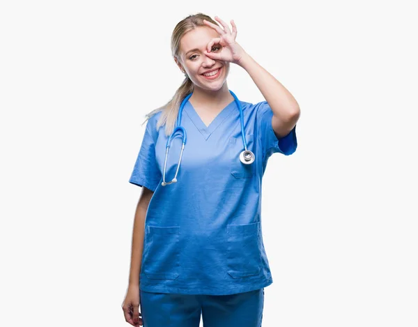 幸せそうな顔で指を通して見る目の手で のジェスチャーを行う分離の背景の上の若い金髪外科医医師女性 — ストック写真