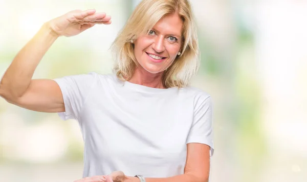 Middle age blonde woman over isolated background gesturing with hands showing big and large size sign, measure symbol. Smiling looking at the camera. Measuring concept.