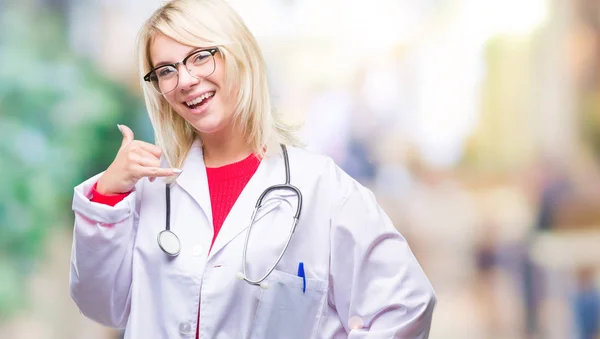 年轻漂亮的金发女医生穿着医疗制服在孤立的背景下微笑着用手和手指做电话手势 就像在电话里聊天一样 沟通理念 — 图库照片