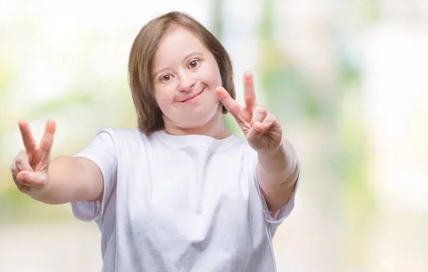 勝利のサインをやって指を表示するカメラを笑みを浮かべて隔離された背景にダウン症候群の若い大人の女性 — ストック写真