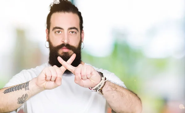 Young hipster man with long hair and beard wearing casual white t-shirt Rejection expression crossing fingers doing negative sign