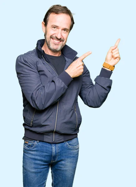 笑顔で側に つの手と指で指しているカメラ目線のジャケットを着て中年ハンサムな男 — ストック写真