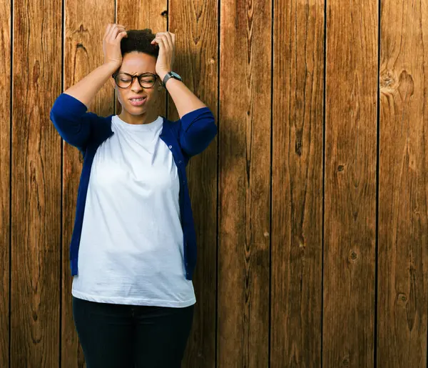 Çünkü çaresiz ve stresli baş ağrısı acı izole arka plan üzerinde gözlüklü genç güzel Afrikalı-Amerikalı kadın ağrı ve migren. Ellerini kafasına.
