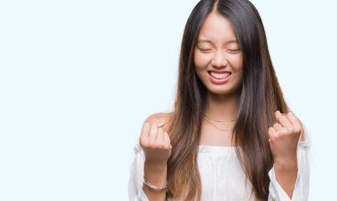 Gülümseyen ve başarı için çığlık Genç Asyalı kadın izole arka plan çok mutlu ve heyecanlı kaldırdı, silah ile kazanan jest yapıyor. Kutlama kavramı.