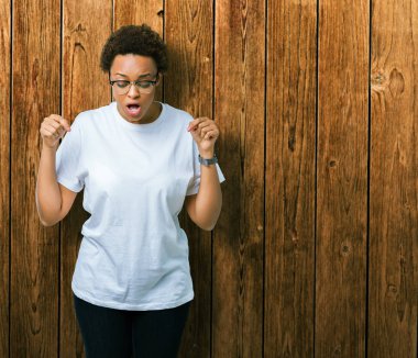 Güzel genç Afro-Amerikan kadın gözlük izole üzerinde işaretleme aşağı reklam, sürpriz yüz ve açık ağız gösterilen parmakları ile arka plan