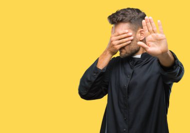 Genç Katolik Hıristiyan rahip adam elleriyle gözlerini kapsayan izole arka plan üzerinde ve stop jest ile acı ve korku ifadesi. Utandım ve negatif kavramı.