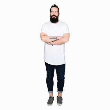 Uzun saç ve sakal görünümlü yan ve dik dik bakma uzağa düşünce gülümseyen casual beyaz t-shirt giyen genç hipster adamla.
