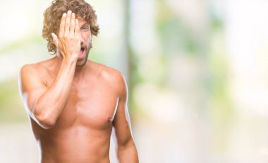 Yakışıklı İspanyol modeli adam seksi ve el yüz ve sürpriz duygu kendinden emin gülümseme ile tek gözüyle kapsayan izole arka plan üzerinde gömleksiz.