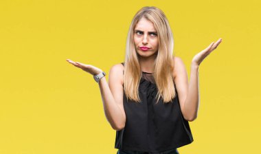 Genç güzel sarışın ve mavi gözlü kadın izole arka plan clueless ve şaşkın bir ifadeyle kollar ve eller kaldırdı. Şüphe kavramı.