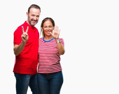Orta yaş İspanyol çift aşık gösterilen ve parmakları ile işaret izole arka plan üzerinde kendinden emin ve mutlu gülümseyerek süre yedi numara.