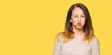 Komik surat ile yanakları şişirme moda kazak giyen güzel orta yaş kadın. Ağız ile hava, deli ifade şişirilmiş.